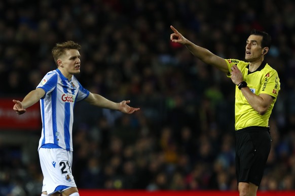 Real Sociedad&#039;s Martin Oedegaard, left, reacts as referee Juan Martinez Munuera points to the penalty box after watching the VAR monitor, during a Spanish La Liga soccer match between Barcelona a ...