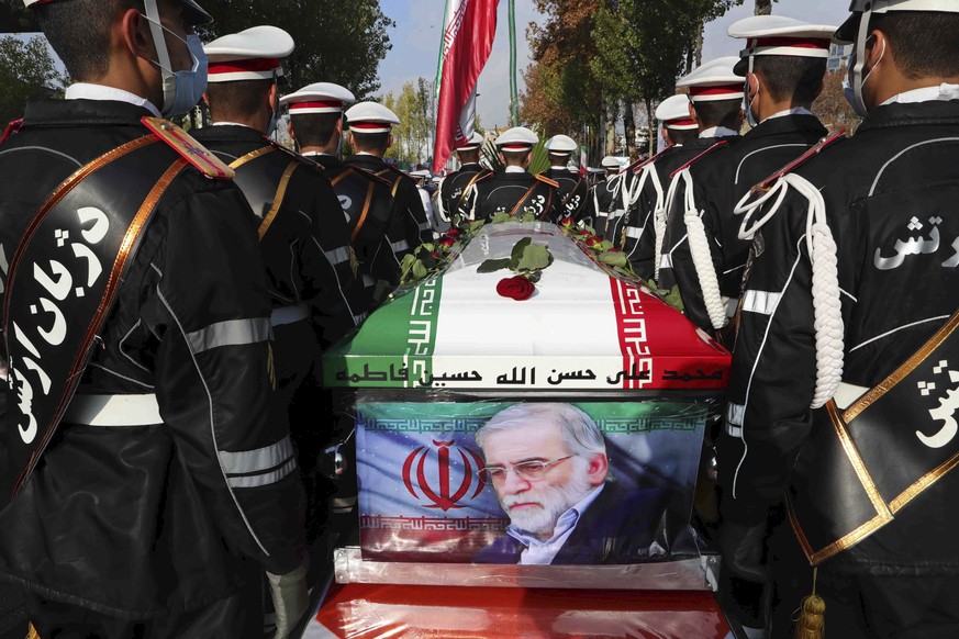 In this photo released by the official website of the Iranian Defense Ministry, military personnel stand near the flag-draped coffin of Mohsen Fakhrizadeh, a scientist who was killed on Friday, during ...
