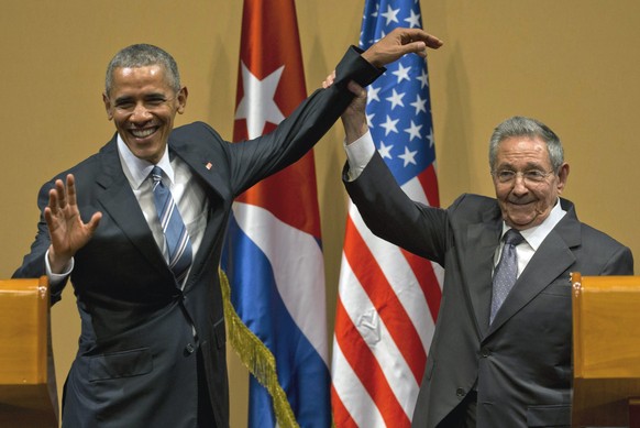 FILE - In this March 21, 2016 file photo, Cuban President Raul Castro, right, lifts up the arm of President Barack Obama at the conclusion of their joint news conference at the Palace of the Revolutio ...