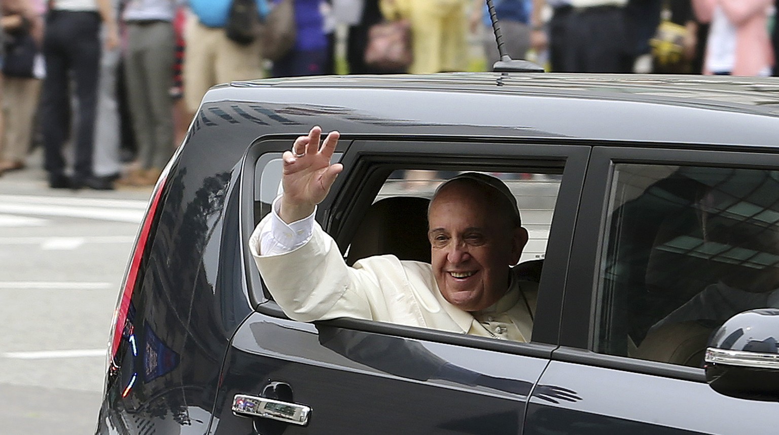 Papst Franziskus winkt aus seinem bescheidenen Auto.