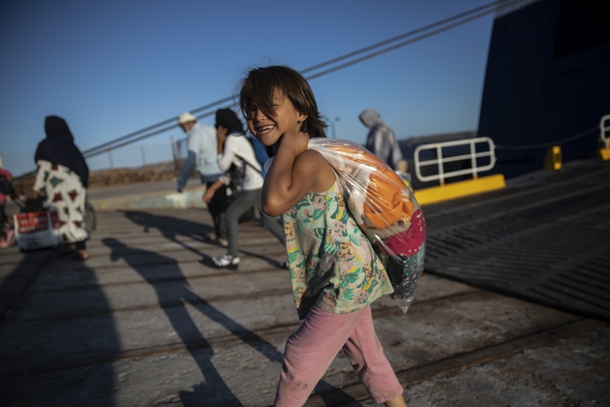 An Afghan girl smiles as she disembarks with other refugees and migrants at the port of Lavrio, about 75 kilometers (48miles) south of Athens, Tuesday, Sept. 29, 2020. Greek authorities have moved nea ...