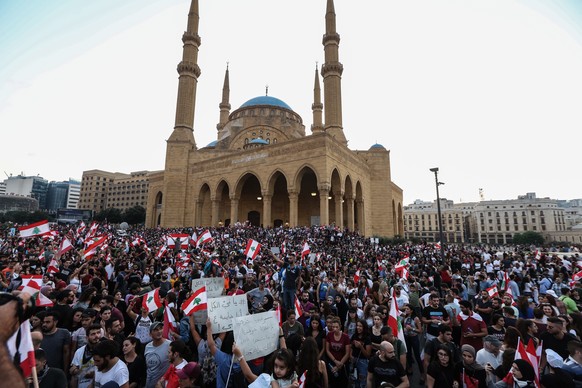 epa07934639 Protesters wave Lebanese flags and shout anti-government slogans during a protest in front the Government palace in downtown Beirut, Lebanon, 19 October 2019. Hundreds of thousands of Leba ...