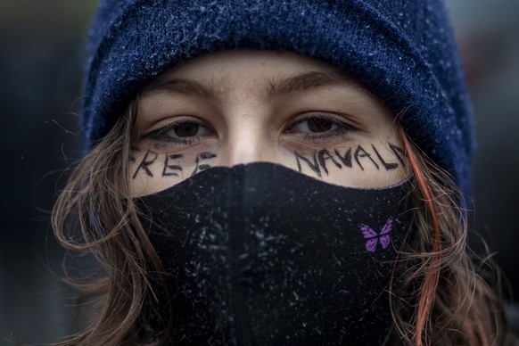 epa08959559 A woman wearing protective face mask writes on her face &#039;Free Navalny&#039; as she takes part in a protest in support of Russian opposition leader and blogger Alexei Navalny, in front ...