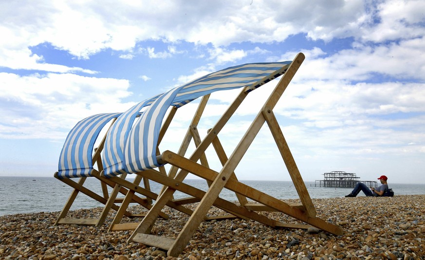 A man relaxes on the beach during the changeable weather, in Brighton, England, Saturday May 25, 2019. (Gareth Fuller/PA via AP)