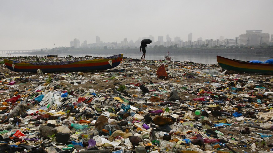 A fisherman walks on the shores of the Arabian Sea, littered with plastic bags and other garbage, in Mumbai, India, Sunday, Oct. 2, 2016. India is scheduled to deposit the ratification instruments of  ...