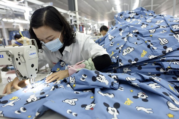 An employee wearing a face mask to protect herself against the coronavirus stitches clothing for export at a factory in Donghai county in eastern China&#039;s Jiangsu Province, Tuesday, Oct. 27, 2020. ...