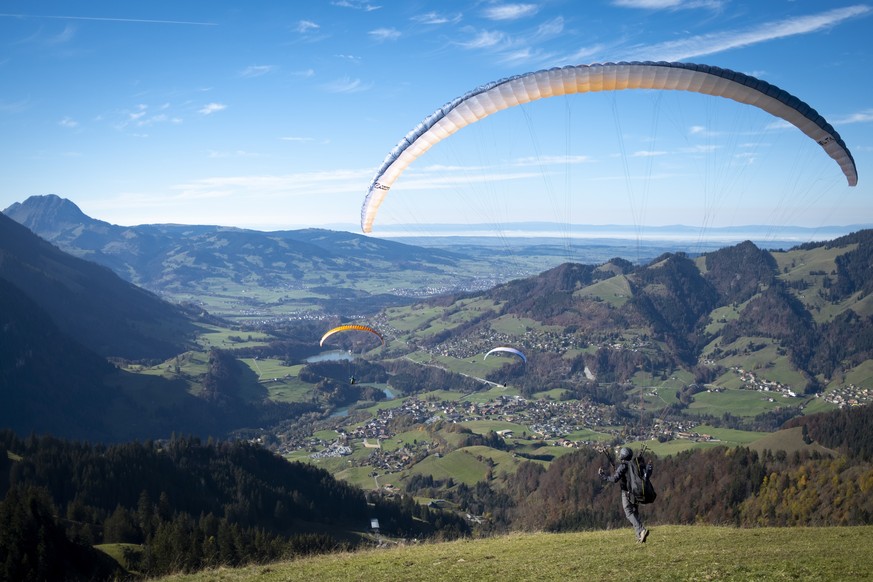 epa08789186 Tourists and paragliders enjoy a sunny autumn weather day in front of Swiss Alps mountains during the second wave pf the coronavirus disease (COVID-19) outbreak, in Charmey, Fribourg, Swit ...