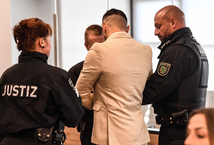 epa07785270 Judicial officers lead defendant Alaa S. (C, back to camera) of Syria into a courtroom prior to the proclamation of the verdict in his trial, at the Higher Regional Court in Dresden, Germa ...