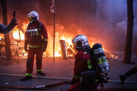 epa08865028 Firefighters prepare to extinguish a fire as several cars burn during a protest against France&#039;s controversial global security law, during a protest in a street between Porte des Lila ...