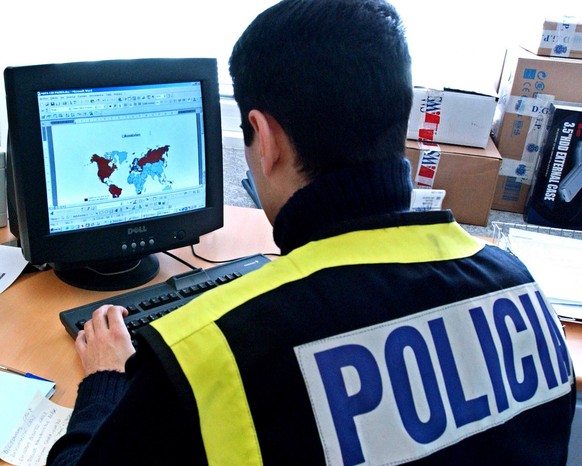 In this undated photo made available from the Spanish Police Saturday Jan. 28, 2006, a Spanish police officer looks at a computer screen during an investigation against child pornography, in Madrid. S ...