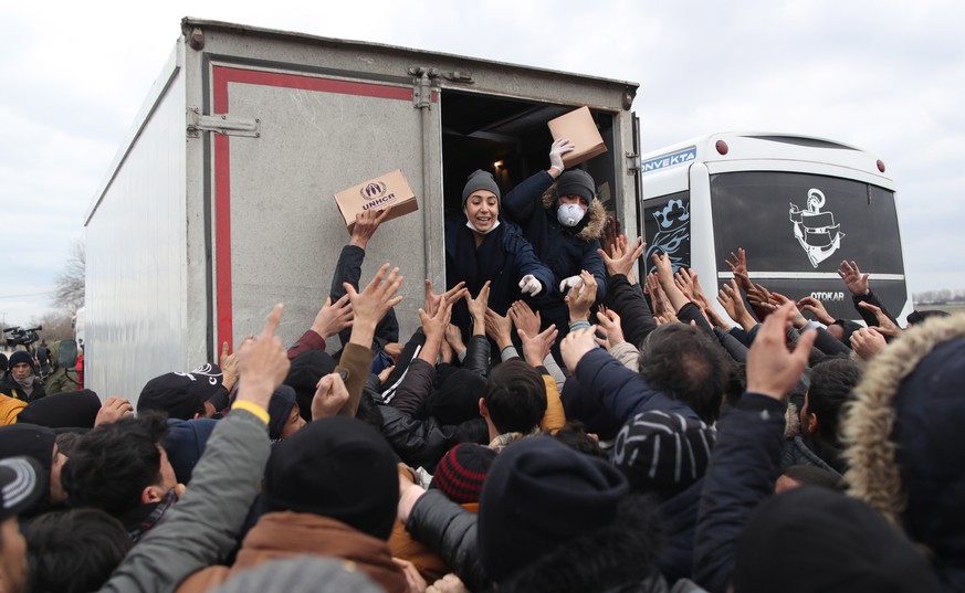 epa08259321 United Nations High Commissioner for Refugees (UNHCR) members distribute food to migrants and refugees that gathered at the Turkish-Greek border, near Edirne, Turkey, 29 February 2020. The ...