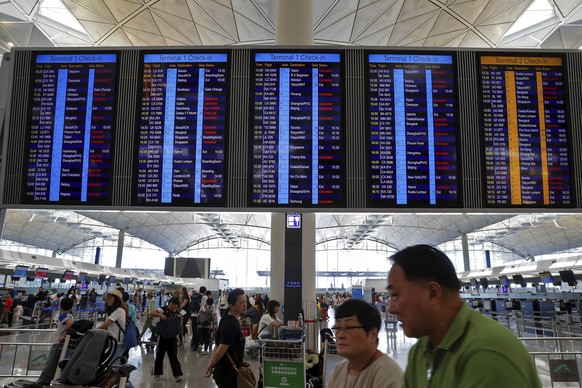 Traveller walk beneath an electronic billboard showing some flight cancellation information at the departure hall of Hong Kong International Airport in Hong Kong, Monday, Aug. 5, 2019. Hong Kong leade ...