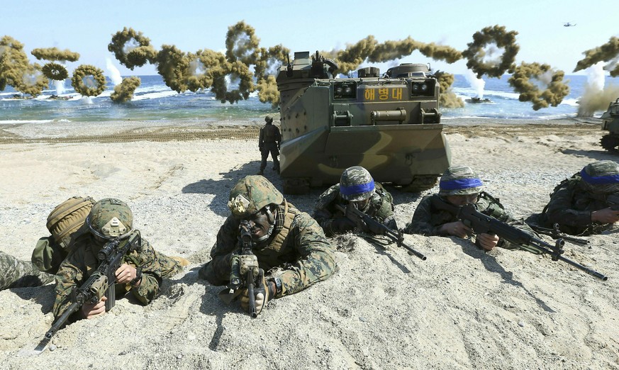 FILE - In this March 12, 2016, file photo, Marines of the U.S., left, and South Korea, wearing blue headbands on their helmets, take positions after landing on a beach during the joint military combin ...
