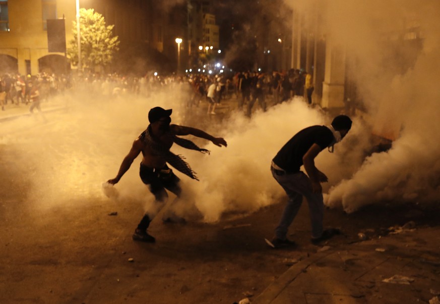 A protester turns back tear gas canister against the Lebanese riot police, during anti-government protest following Tuesday&#039;s massive explosion which devastated Beirut, Lebanon, Sunday, Aug. 9. 2 ...