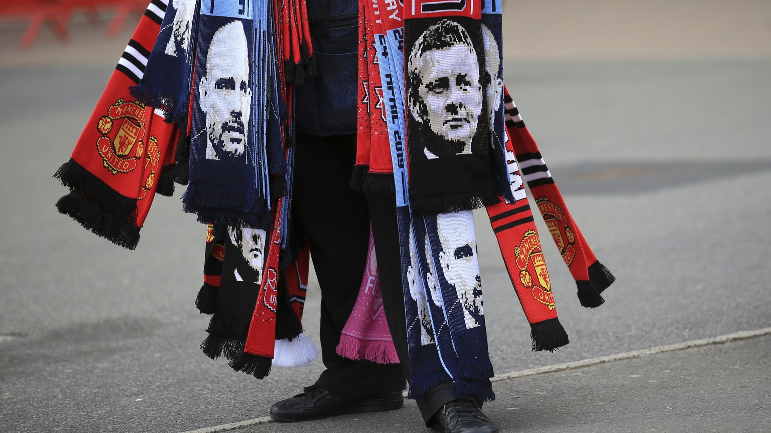 A man sells scarves with pictures of Manchester United manager Ole Gunnar Solskjaer and Manchester City coach Pep Guardiola, left, outside the stadium before before the English Premier League soccer m ...