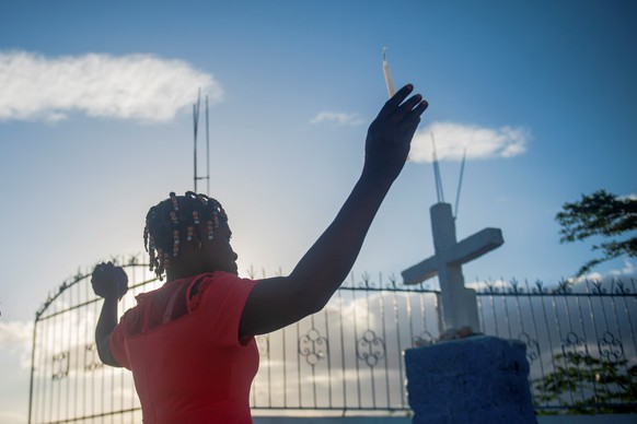 epa09112696 A woman participates in a pilgrimage during the commemoration of Holy Friday, through the mountains of Port-au-Prince, Haiti, 02 April 2021. Hundreds of members of Haitian Catholic and Voo ...
