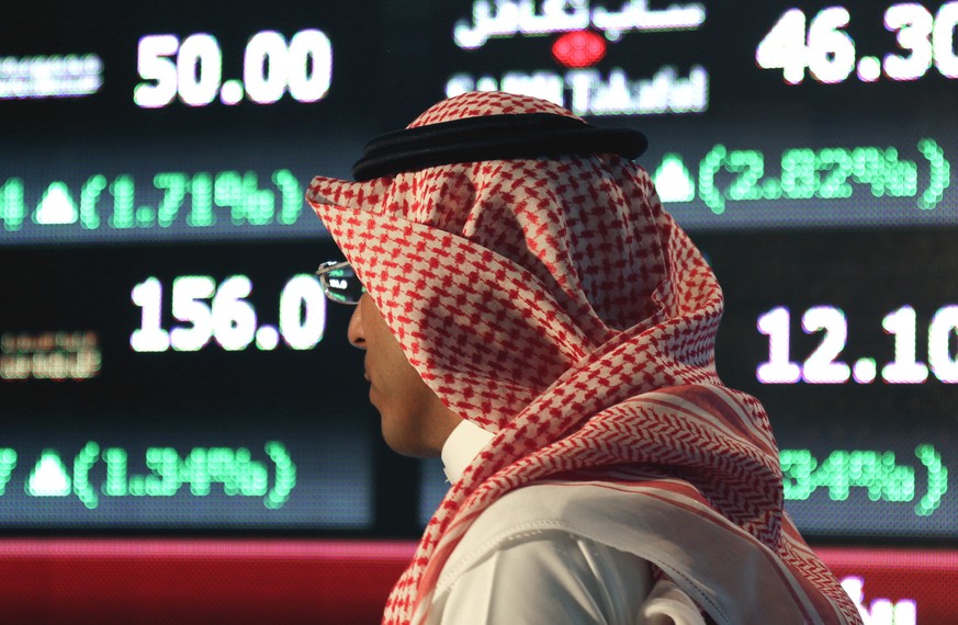 FILE - In this June 15, 2015, file photo, a Saudi man walks through the Tadawul Saudi Stock Exchange in the Saudi Arabian capital, Riyadh. Saudi ArabiaÄôs renewed push to publicly list its most valua ...