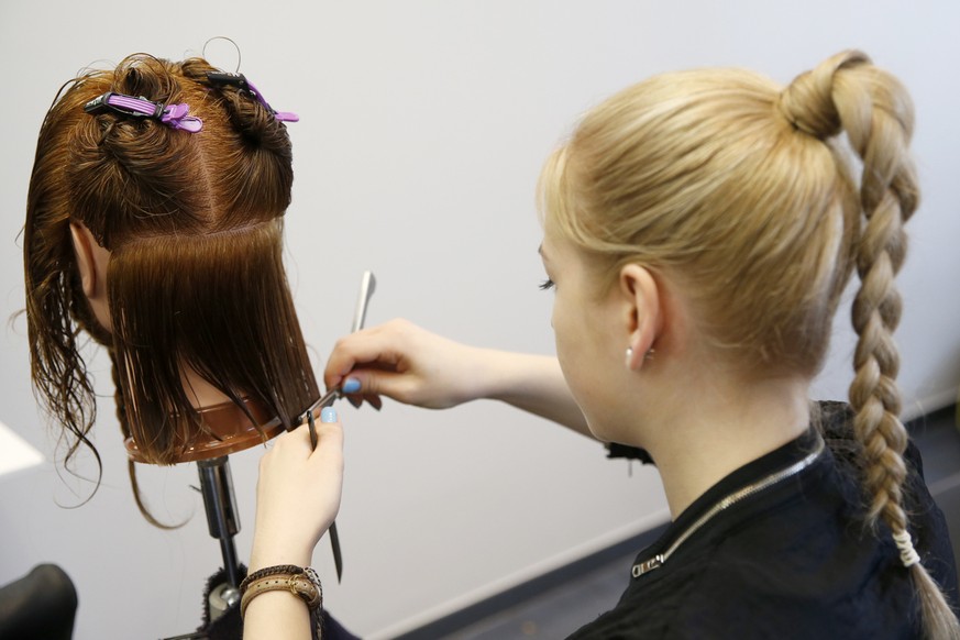Madlen Huber, Coiffeur Lernende im 3. Lehrjahr, schneidet das Haar an einem Modell-Kopf mit Echthaar, am Dienstag, 31. Maerz 2015 in Bern. (KEYSTONE/Peter Klaunzer)