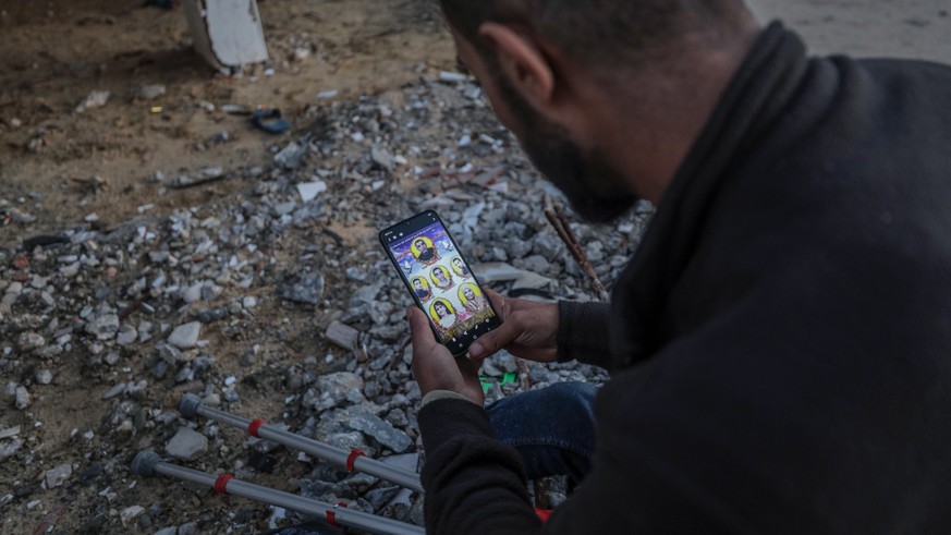 epa08906739 Mahmoud Moussa, looks at photos of his family through his mobile phone in Gaza City, 27 December 2020. Moussa was injured in 14 January 2008, during the 2008-2009 Israeli war against Gaza  ...