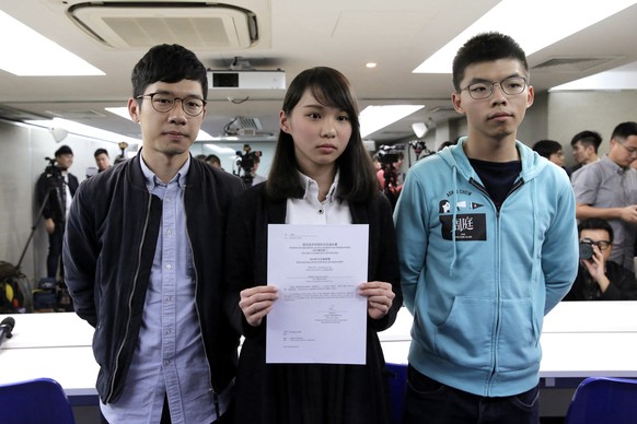 In this Jan. 27, 2018, photo, Agnes Chow, center, a member of democracy Demosisto party, is accompanied by Joshua Wong, right, and Nathan Law, holds a notice from the Hong Kong government at a press c ...