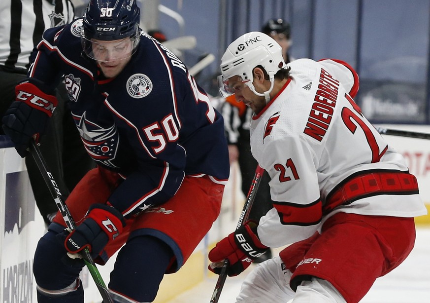 Columbus Blue Jackets&#039; Eric Robinson, left, and Carolina Hurricanes&#039; Nino Niederreiter fight for a loose puck during the second period of an NHL hockey game Monday, Feb. 8, 2021, in Columbus ...