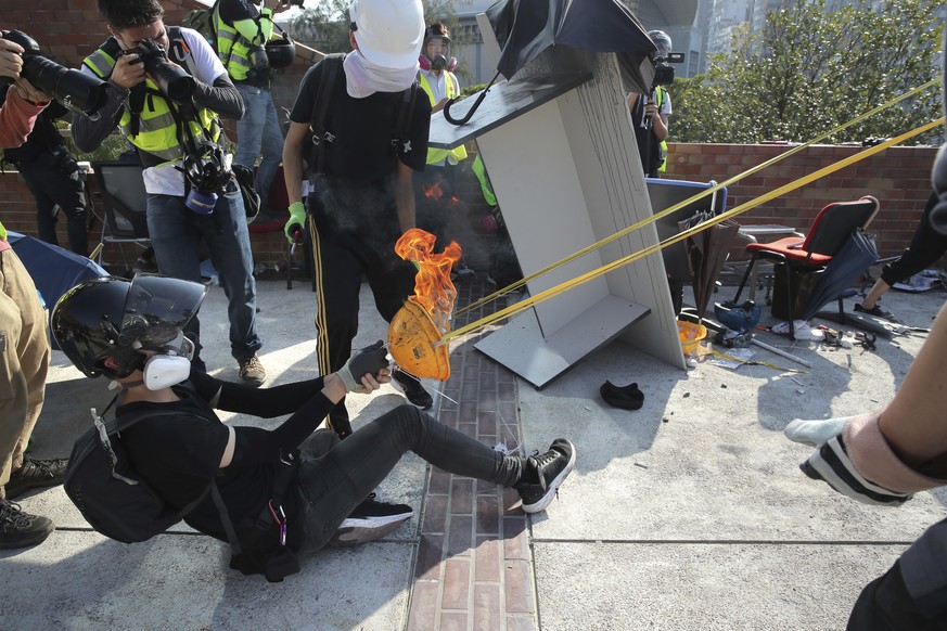 Protestors use an improvised slingshot to fire a molotov cocktail during a confrontation with police at Hong Kong Polytechnic University in Hong Kong, Sunday, Nov. 17, 2019. A Hong Kong police officer ...