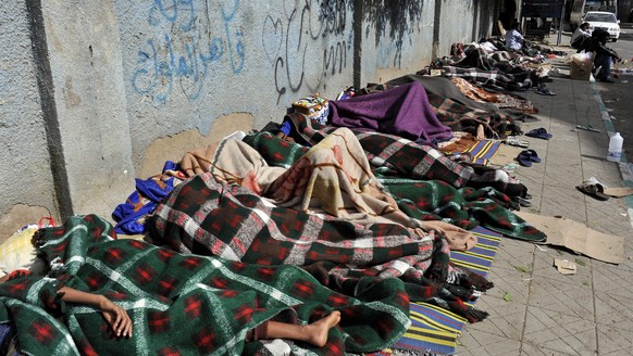 epa04190193 Eritrean refugees sleep on the sidewalk of a street as they wait for help from UNHCR in Sana’a, Yemen, 03 May 2014. Reports state over 210 Eritrean refugees, including women and children,  ...