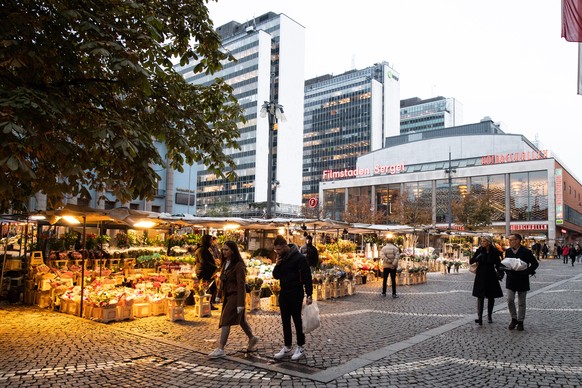 epa08786508 People walk past flower stalls at Hotorget square in central Stockholm, Sweden, 30 October 2020. The Public Health Agency of Sweden has tighten their recommendations for five regions in Sw ...