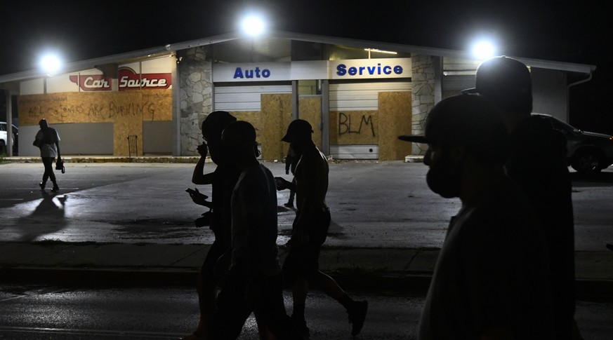 epa08628279 Protestors walk by the scene where someone was fatally shot Tuesday night during demonstrations over the shooting of Jacob Blake during a fourth night of unrest in the wake of the shooting ...