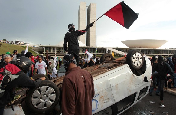 epa05652746 Protesters overturn a vehicle outside the Brazilian Congress, during a protest against the fiscal adjustment promoted by the government of President Michel Temer and for maneuvers that may ...