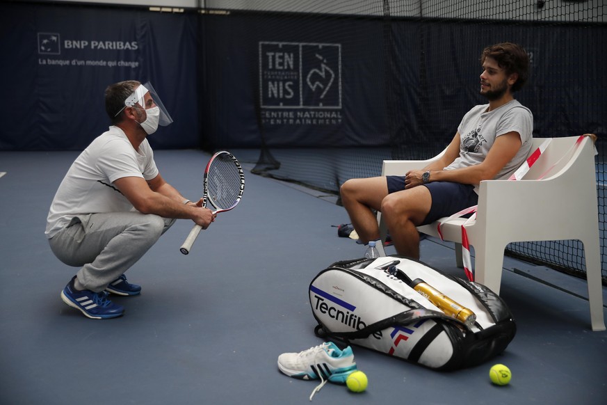 French tennis player Gregoire Barrere, right, and courtside trainer Marc Gicquel, left, attend a training session in the French Tennis Federation center near the grounds of the French Open in Paris, W ...