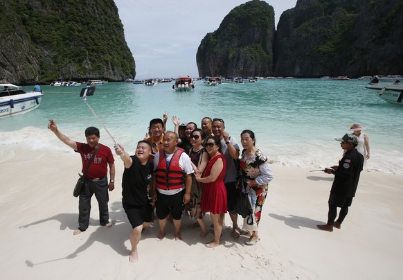 Tourists take selfies on the beach of Maya Bay, Phi Phi Leh island in Krabi province, Thailand, Thursday, May 31, 2018. The popular tourist destination of Maya Bay in the Andaman Sea will close to tou ...