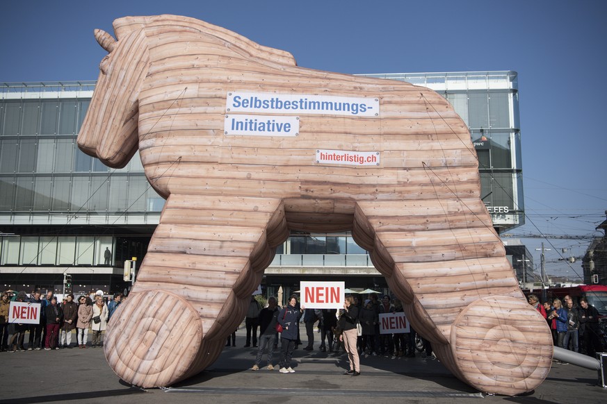 Personen demonstrieren mit Plakaten und einem Trojanischen Pferd gegen die Selbstbestimmungs-Initiative der SVP, am Montag, 22. Oktober 2018, in Bern. (KEYSTONE/Peter Schneider)