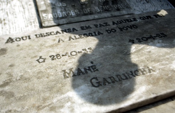 A man casts his shadow over the grave of former Brazilian soccer player Mane Garrincha, with an inscription that&#039;s read: &quot;Here rests in peace the one who was the Joy of the People - Mane Gar ...