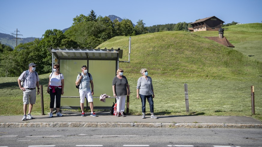 Eine Gruppe Wanderer wartet auf das Postauto bei der Haltestelle Sagendorf in Emmetten im Kanton Nidwalden am zweiten Tag der Schutzmaskenpflicht im oeffnetlichen Verkehr waehrend der Corona-Pandemie  ...