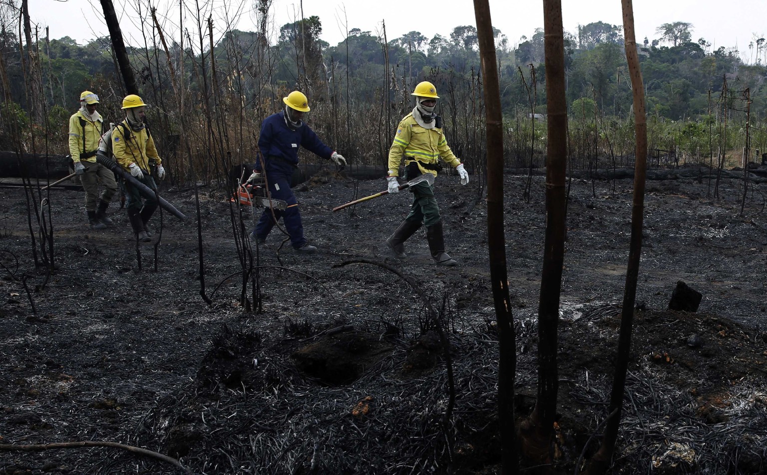 Firefighters walk across charred land to another area as they work to put out fires in the Vila Nova Samuel region, along the road to Jacunda National Forest near the city of Porto Velho in Rondonia s ...
