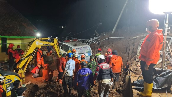 In this photo provided by the Indonesian National Disaster Mitigation Agency, rescuers work the scene of a landslide in Cihanjuang village, Indonesia, early Sunday, Jan. 10, 2021. Two landslides in th ...