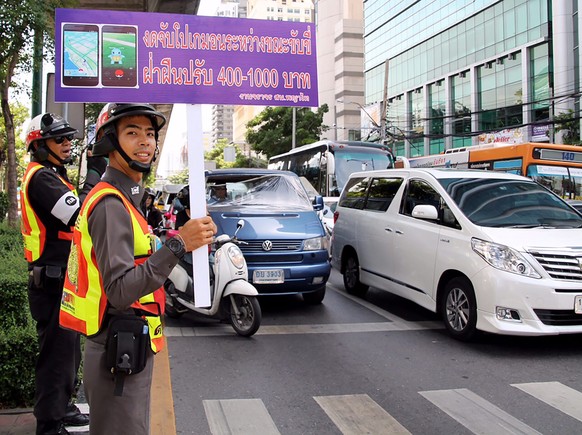 epa05506563 A Thai traffic policeman holds a banner reading &#039;No Pokemon Go while driving, violators will be fined&#039; during the &#039;Pokemon Traffic No Go&#039; campaign at a busy street in B ...