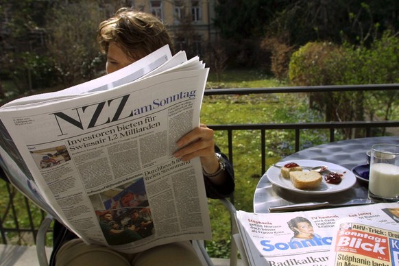 Eine Zeitungsleserin studiert am Sonntag, 17. Maerz 2002 in Bern zum Fruehstueck die erstmals erschienene NZZ am Sonntag. Neben der Sonntagszeitung und dem Sonntagsblick ist die NZZ der dritte deutsch ...