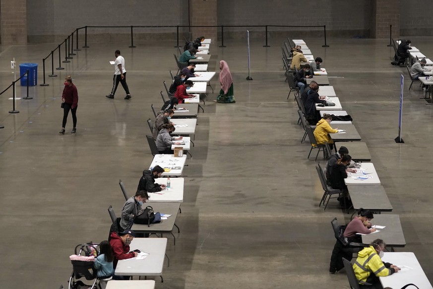 Voters sit spread out as they fill out ballots while voting at the CenturyLink Field and Event Center Tuesday, Nov. 3, 2020, in Seattle. (AP Photo/Ted S. Warren)