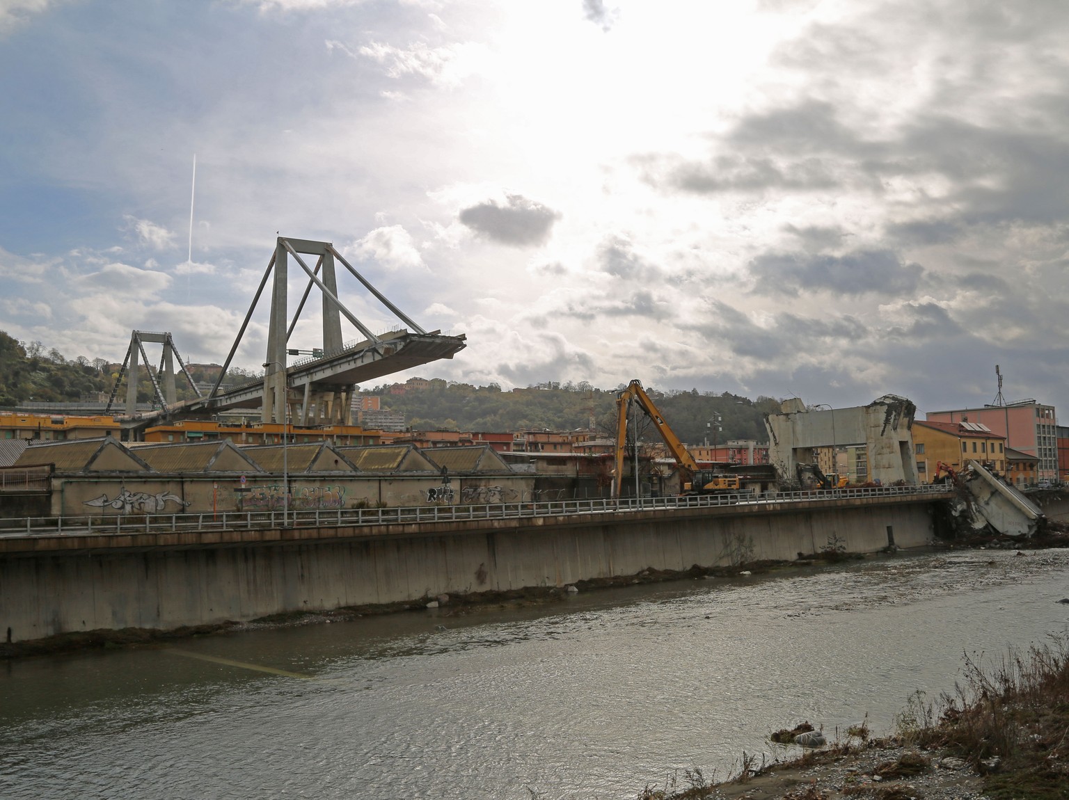 Blick auf die abgebrochene Morandi-Brücke: Unten fliesst der Polcevera-Fluss durch, rechts bauen Bagger den kaputten Pfeiler ab.&nbsp;&nbsp;