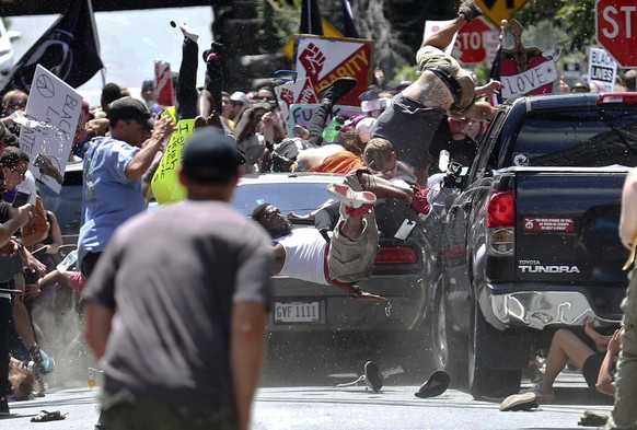 People fly into the air as a vehicle drives into a group of protesters demonstrating against a white nationalist rally in Charlottesville, Va., Saturday, Aug. 12, 2017. The nationalists were holding t ...