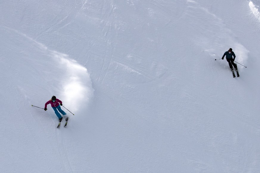 Skifahrer mit Atemschutzmasken fahren Ski auf dem Titlis, am Dienstag, 10. November 2020. Auf allen Sesselbahnen, Skiliften und Seilbahnen des Skigebietes gilt Maskenpflicht. (KEYSTONE/Alexandra Wey)