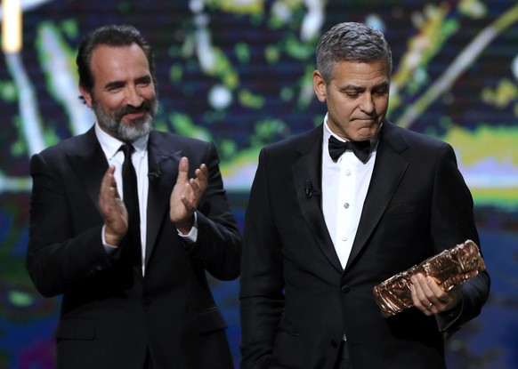 Actor George Clooney (R) looks at his trophy next to actor Jean Dujardin after receiving an Honorary Cesar Award at the 42nd Cesar Awards ceremony in Paris, France, February 24, 2017. REUTERS/Philippe ...