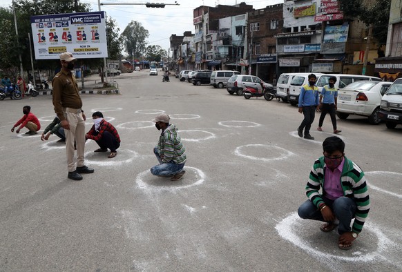 epa08320839 Jammu and Kashmir police officers force people to crouch inside a marked circle to maintain a minimum social distance after they allegedly violated Section 144 (gathering of more than thre ...