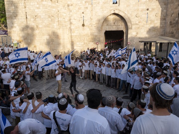 epa07620659 Right-wing Israeli youth dance with Israeli flags as they march into the Damascus Gate (behind) in East Jerusalem and enter the Old City&#039;s Muslim Quarter as they make their way to the ...
