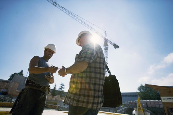 Ein Kontrolleur prueft am 17. August 2005 auf einer Baustelle in Bern die Arbeitsbewilligung eines Arbeiters auf einer Baustelle. Damit soll die Garantie des Arbeitsnehmers auf Renten- und Versicherun ...