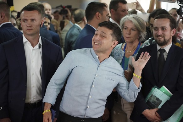 Ukrainian President Volodymyr Zelenskiy, center, gestures as he arrives at a polling station during a parliamentary election in Kiev, Ukraine, Sunday, July 21, 2019. Ukrainians are voting in an early  ...