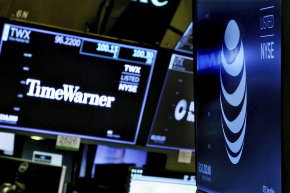 The logos for Time Warner and AT&amp;T appear above alternate trading posts on the floor of the New York Stock Exchange, Wednesday, June 13, 2018. A federal judge has approved the $85 billion mega-mer ...