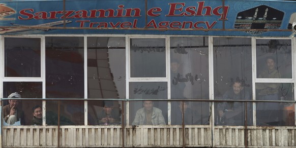 Afghans look from the window of a shop after an attack in Kabul, Afghanistan, Friday, March 6, 2020. Gunmen in Kabul attacked a remembrance ceremony for a minority Shiite leader on Friday, wounding mo ...